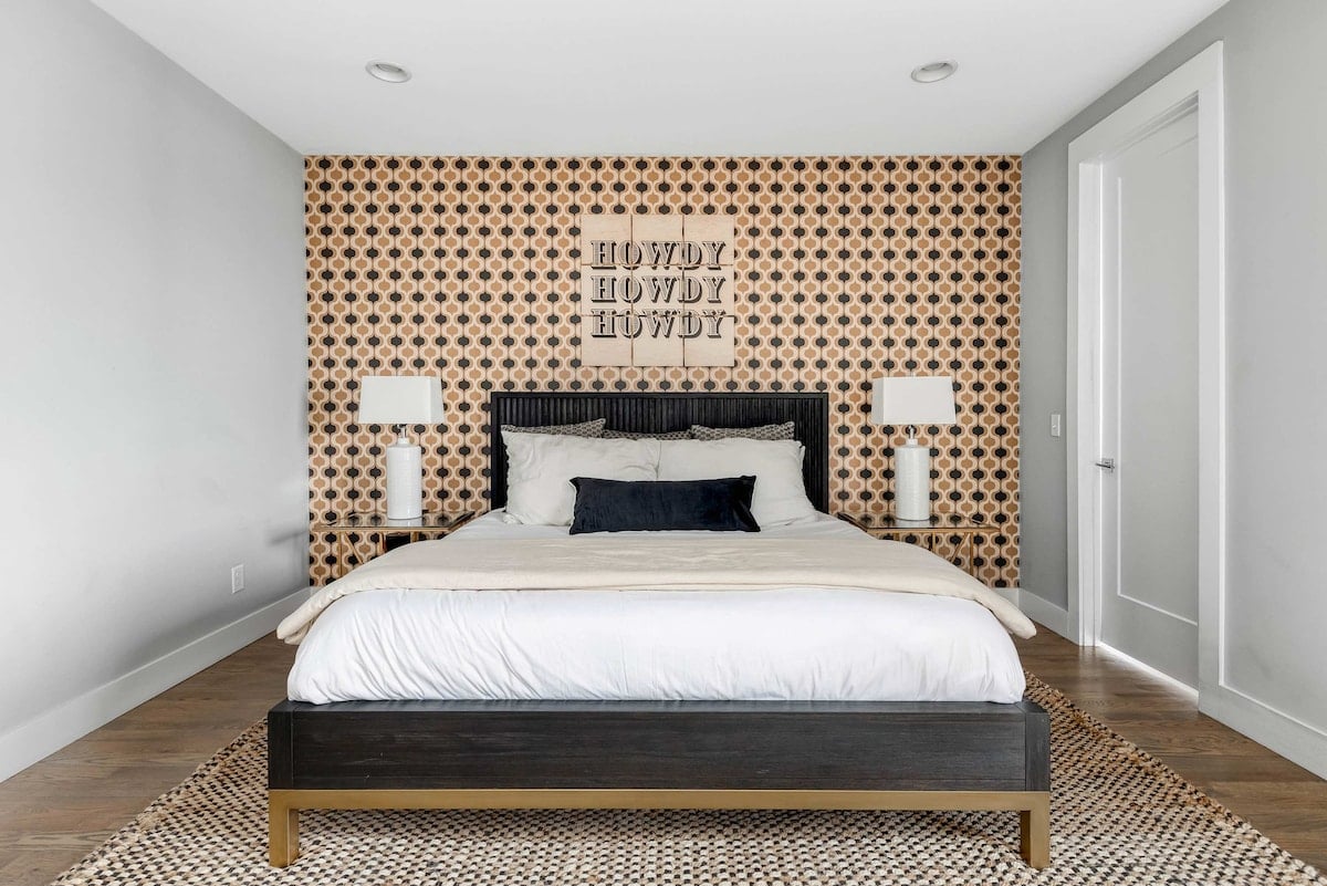 The oversized master bedroom offers a spacious and luxurious retreat, highlighted by a large king-sized bed as the centerpiece. The room exudes sophistication, featuring a stylish feature wall adorned with a bold, eye-catching wallpaper.