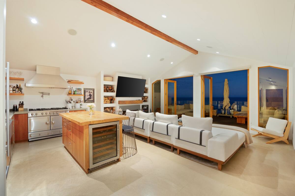 Large glass doors open to the rustic beachfront deck. 
