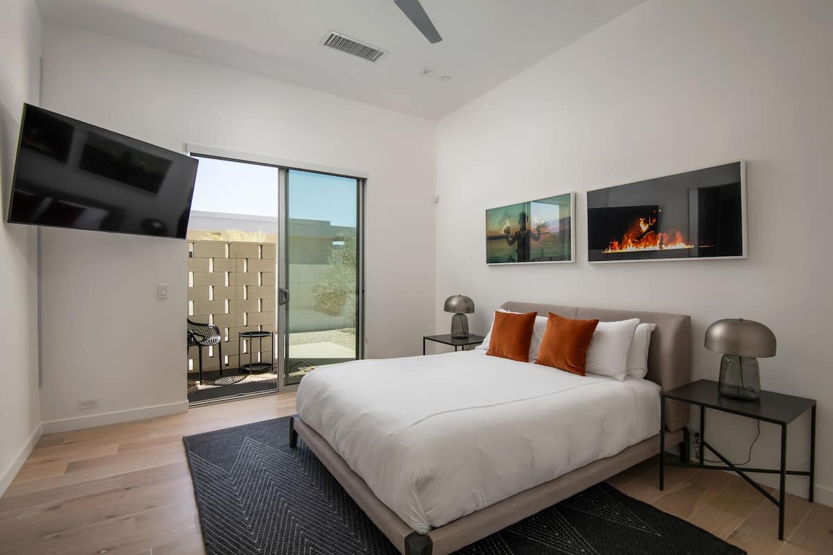 A comfortable queen suite featuring a smart TV, modern desert art, and private sliding door access to the outdoor patio.
