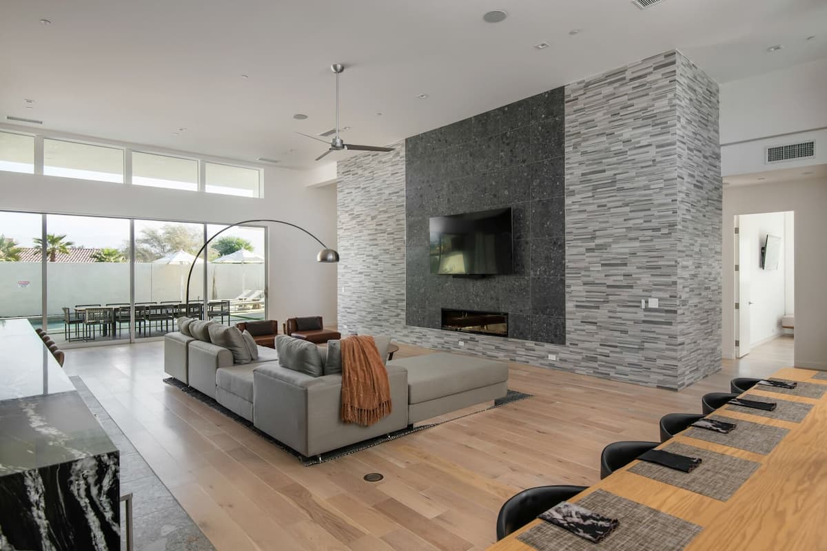 The stunning great room centers on a floor-to-ceiling stone fireplace wall, a large smart TV, and comfortable sectional seating.