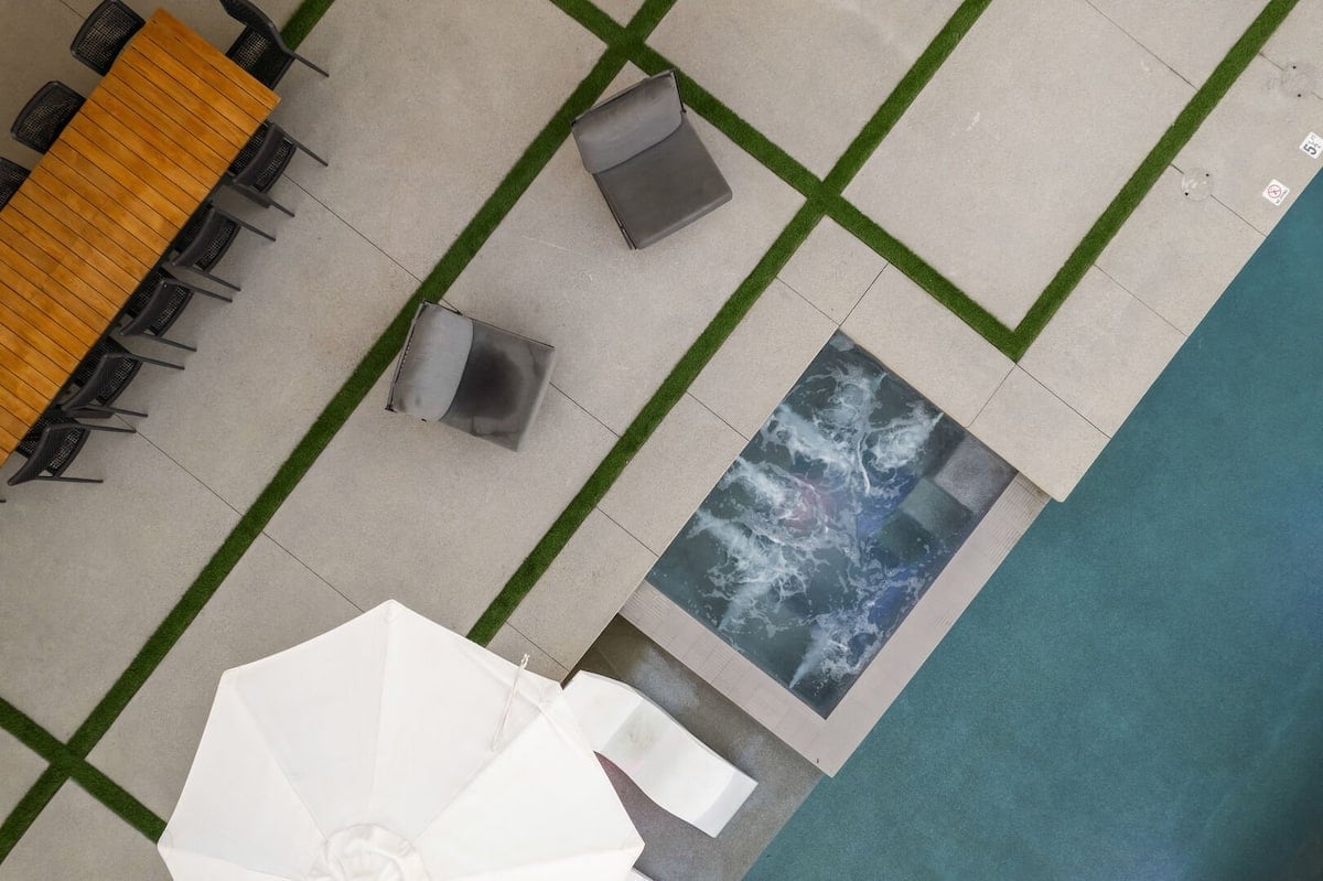 An overhead shot detailing the heated hot tub and pool ledge, perfectly situated next to the outdoor dining area.