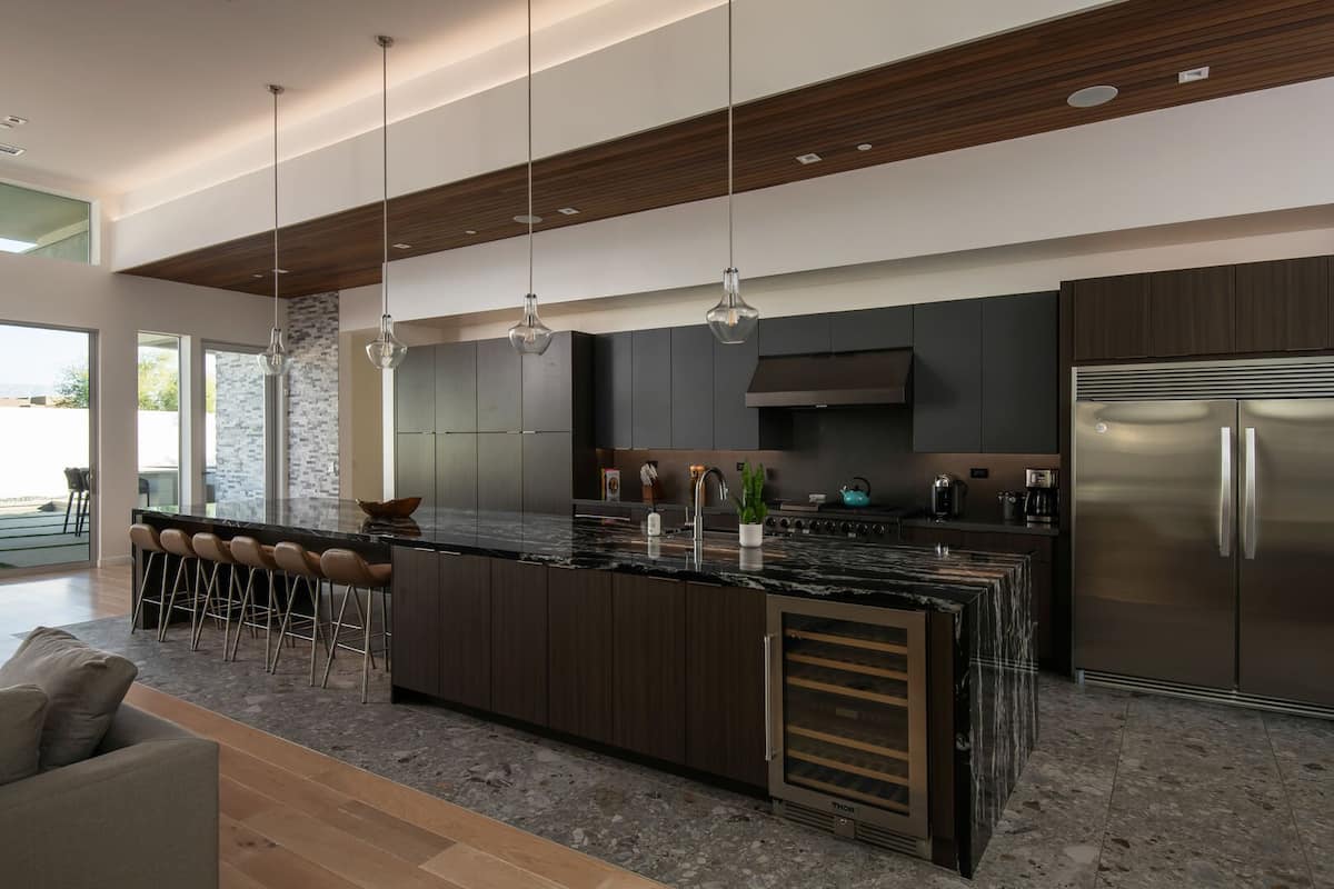 The gourmet chef's kitchen features a massive marble island with seating, a built-in wine cooler, and professional-grade appliances.