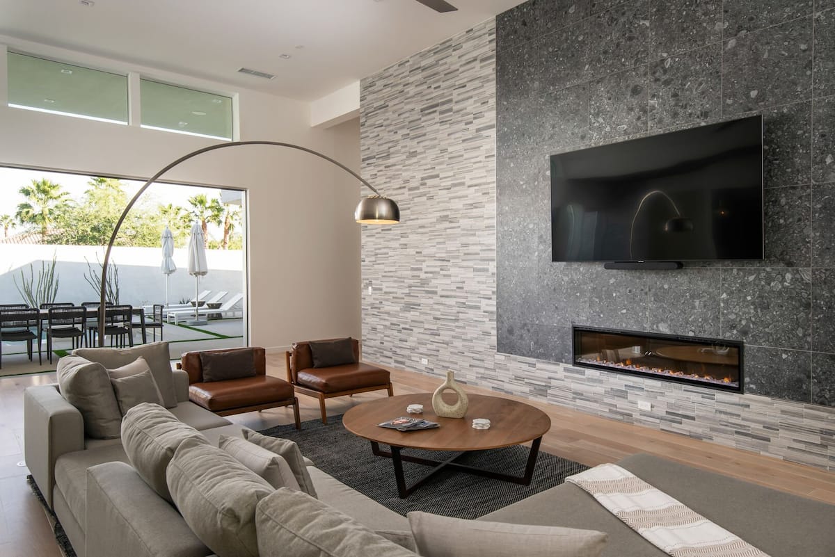 The centerpiece of the great room: a comfortable sectional facing the modern stone fireplace and large smart TV.