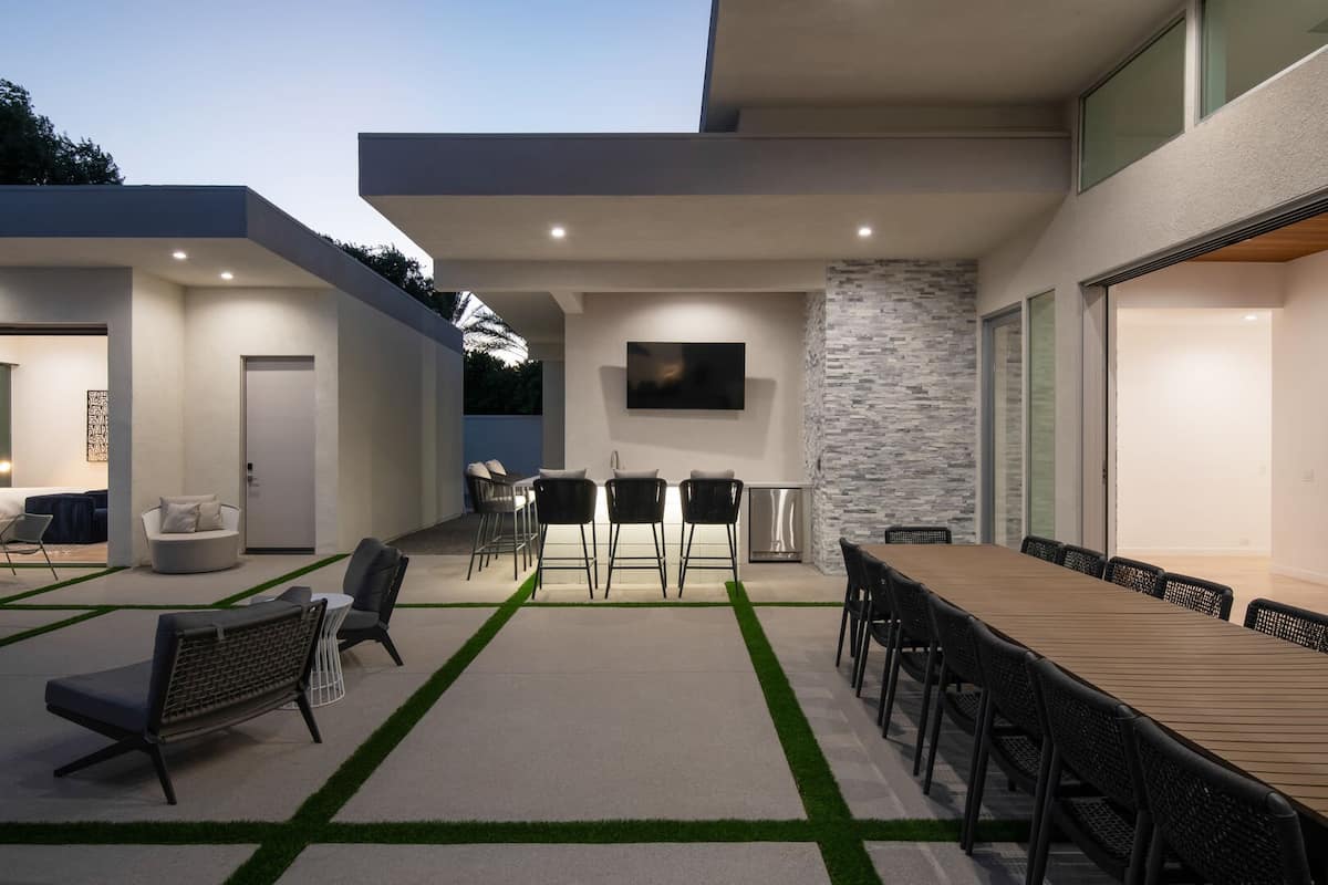 The covered outdoor entertaining area, featuring a massive dining table for 10+, a wet bar, and the seamless transition from the interior.