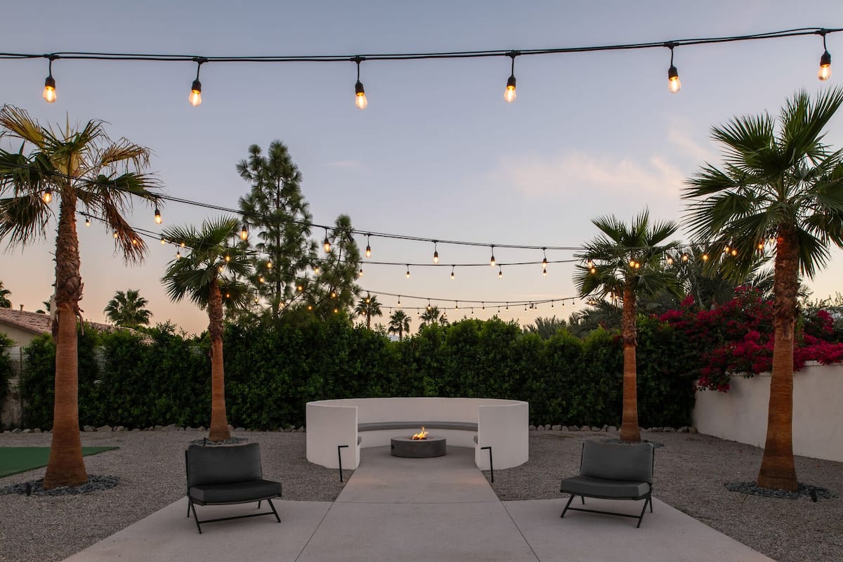 The stunning custom fire pit lounge under string lights, offering a cozy and intimate gathering space after dark.