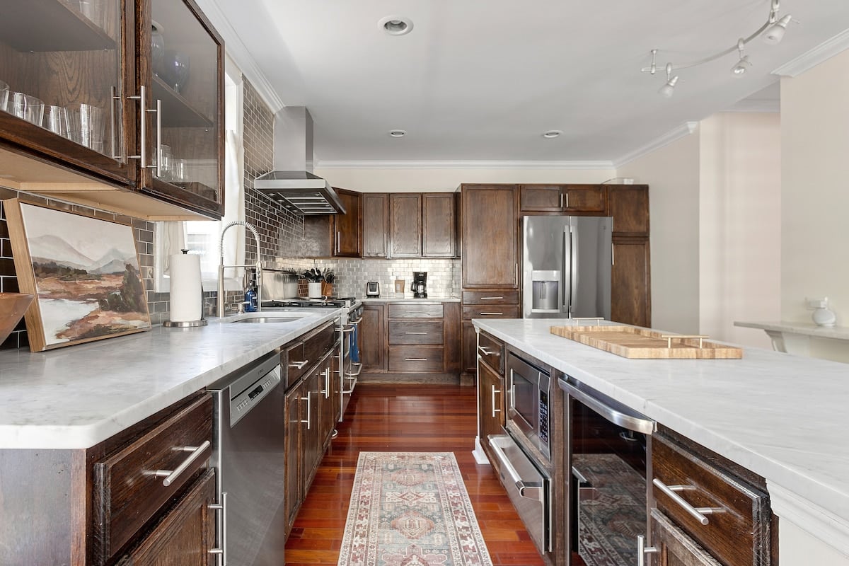 CAPTION: "Property" in Charleston combines modern luxury with classic southern charm. Featuring sleek stainless steel appliances and rich wooden cabinetry, the kitchen exudes sophistication and warmth. The use of a contemporary neutral color palette enhances its elegant design, creating an inviting atmosphere. Perfect for gourmet enthusiasts and those seeking refined comfort, this exquisite space is ideal for travelers looking to experience opulence in Charleston's vibrant setting.