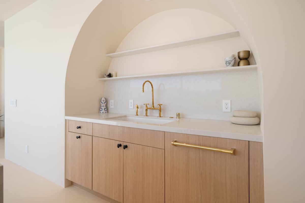 Below the kitchen archway sits built-in Cafe GE appliances with bronze finishes.