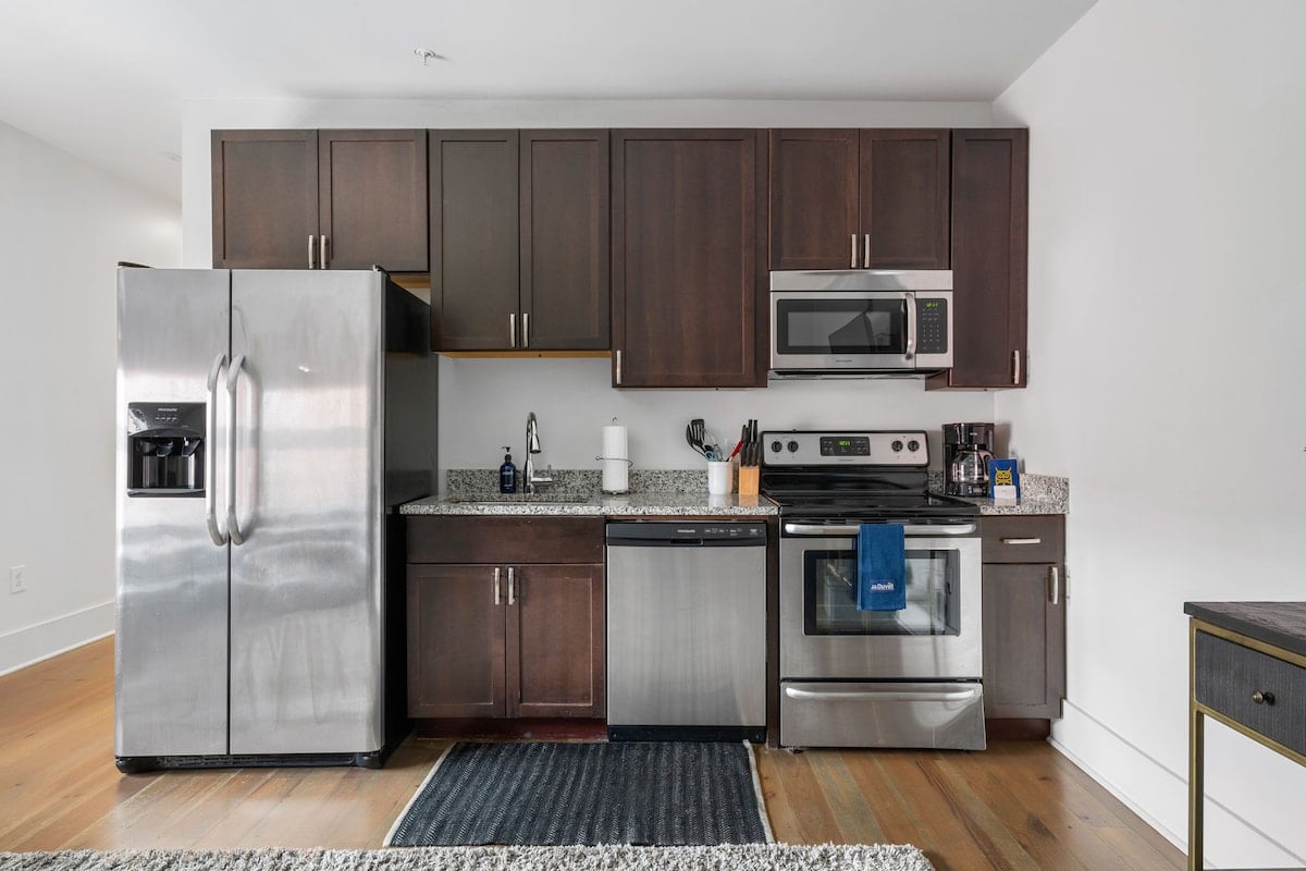 CAPTION: Discover the sophisticated charm of "Property" in Charleston, US. This modern kitchen features sleek stainless steel appliances and richly stained wooden cabinetry, creating a warm and inviting atmosphere. The subtle contrast of the granite countertops adds a touch of elegance, while the contemporary gray and white color palette enhances the overall aesthetic appeal. Ideal for luxury travelers seeking comfort and style, this chic space blends contemporary design with Southern hospitality.