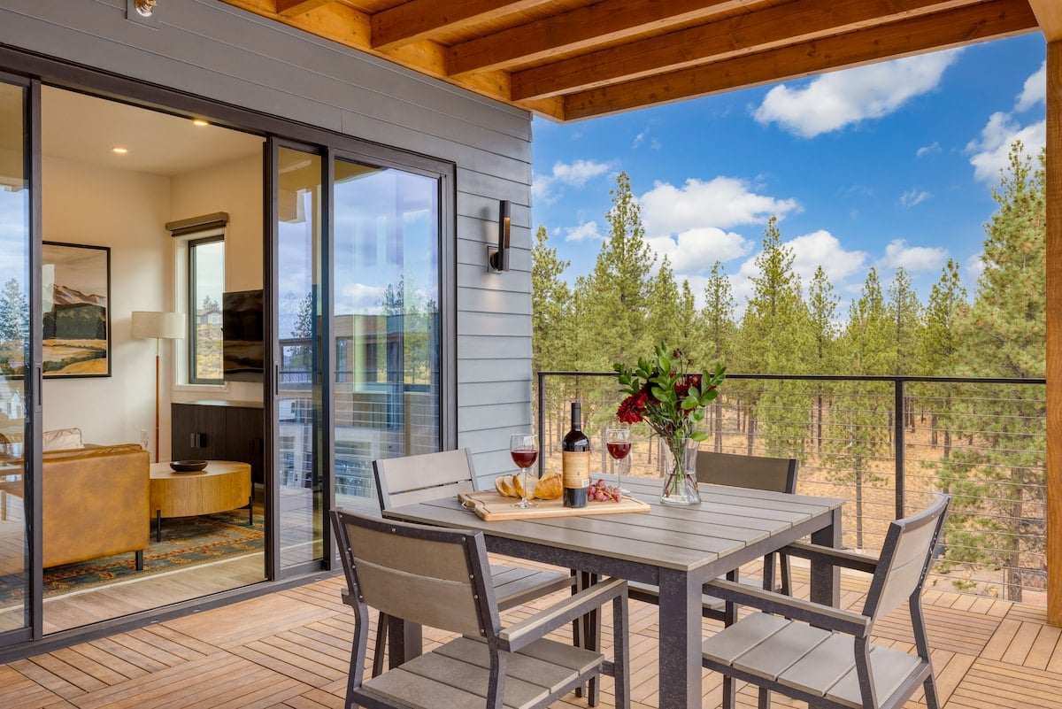 Covered balcony with outdoor dining and forest views.