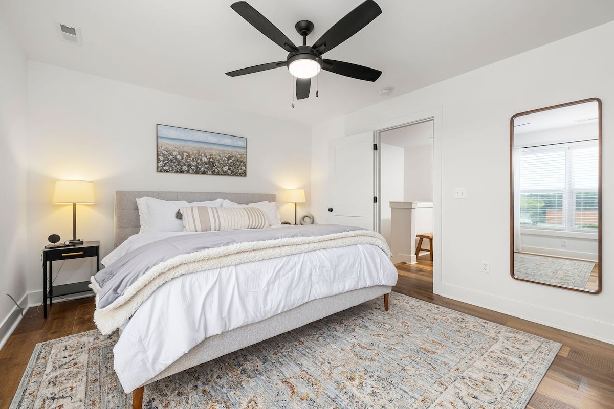 The primary bedroom has a view of the city, king bed, dresser, TV, walk-in closet, and attached primary bathroom.