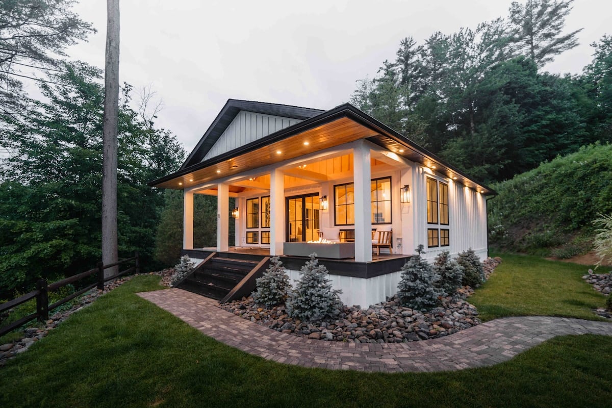 CAPTION: Nestled in the serene landscapes of Remsen, "Property" exudes modern rustic charm with its cozy yet sophisticated architectural style. The inviting atmosphere is enhanced by a harmonious blend of natural materials, featuring a warm color palette of whites and earth tones. Expansive windows and a spacious porch create an airy ambience, perfect for nature lovers seeking tranquility. Ideal for luxury travelers, this property offers a refined escape with its picturesque backdrop and elegant design.