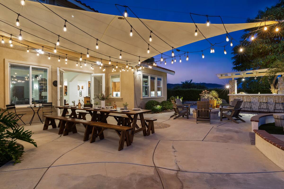 Entertainment area outside with a picnic table, string lights, fire pit, and built-in BBQ.