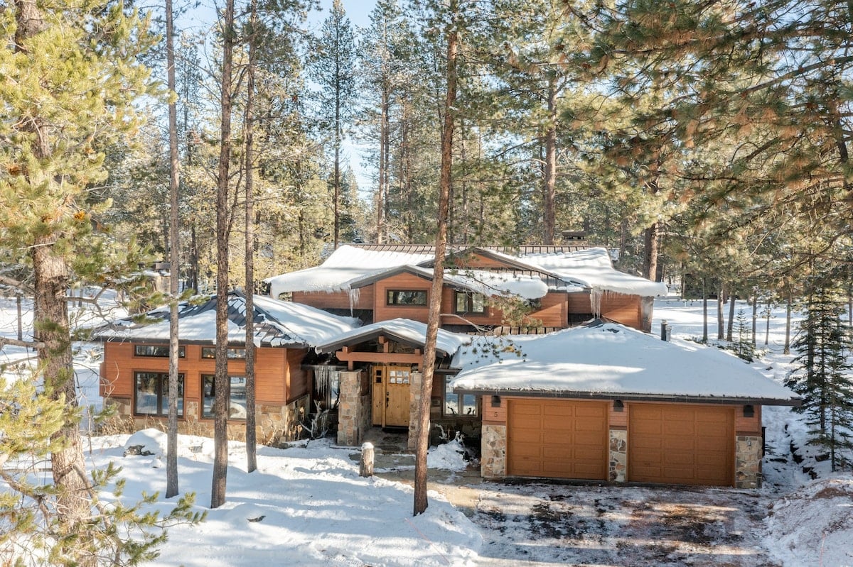 CAPTION: Nestled amidst a tranquil forest in Bend, the "Property" exemplifies rustic elegance with its modern cabin architectural style. This luxurious retreat features a harmonious blend of wood and stone, complemented by a serene winter landscape. The warm earth tones of the facade contrast beautifully with the snowy surroundings, creating a cozy yet lavish escape. Ideal for nature enthusiasts and luxury travelers seeking a peaceful mountain getaway, this property promises a truly enchanting experience.