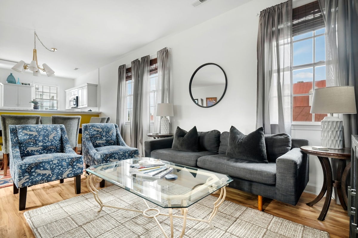 CAPTION:
Nestled in the heart of Charleston, "Property" exudes Southern charm with its contemporary coastal design. The bright, airy living space features plush blue armchairs, a sleek gray sofa, and large windows allowing natural light to illuminate the room. The neutral palette is accented with subtle pops of color, creating a soothing atmosphere. A glass-top coffee table adds modern elegance, ideal for travelers seeking comfort and style. Perfect for those exploring Charleston's historic allure.