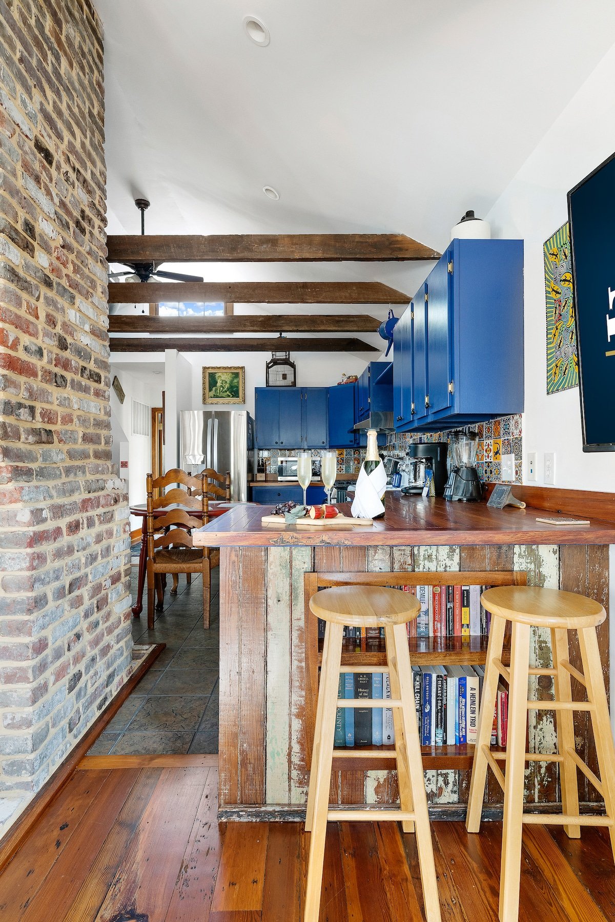 CAPTION: Discover the allure of "Property" in Charleston, a charming blend of rustic and modern sensibilities. This inviting space features a stunning combination of exposed brick walls, vibrant blue cabinets, and unique wooden beams. The warm wooden floors and eclectic kitchen island infuse the room with a cozy, welcoming atmosphere. Perfect for travelers seeking a stylish yet homey ambiance. Ideal for guests looking for a distinctive experience with a touch of Southern charm.