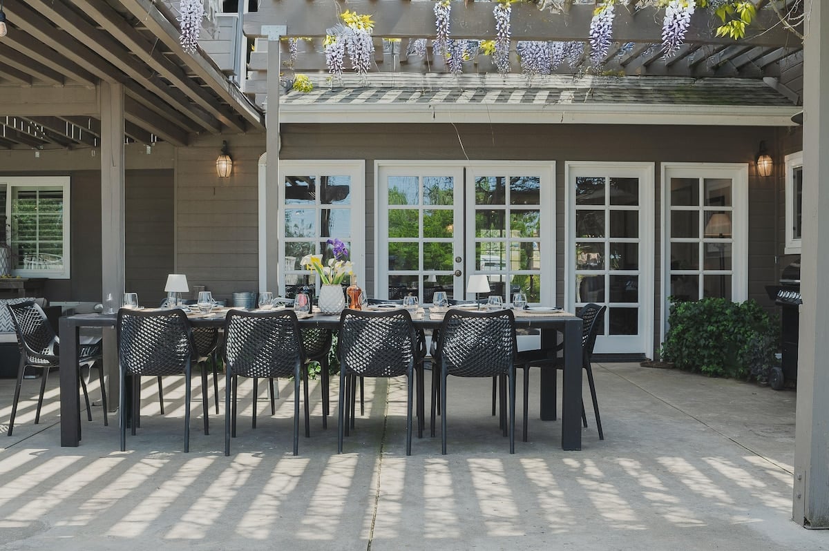 Outdoor dining table seats 10, with hanging wisteria shade and easy access to the living room and kitchen via the French doors. 