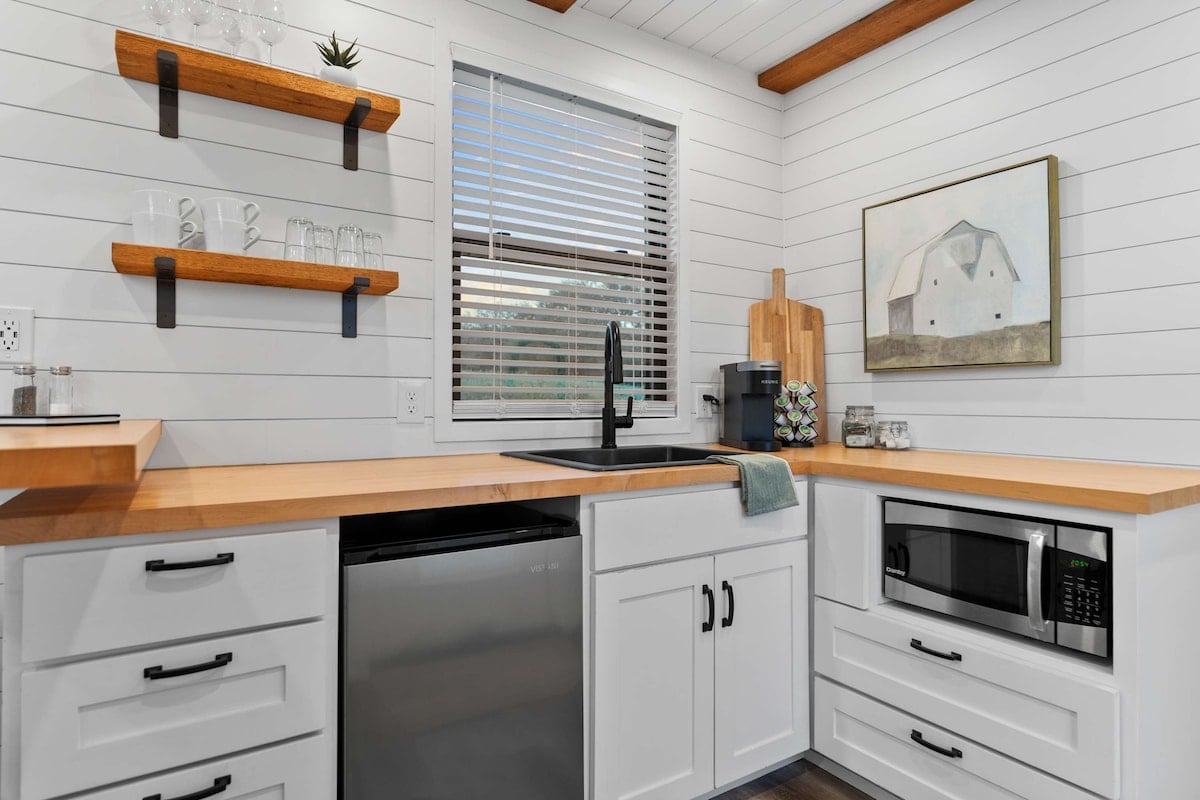 The kitchen features an under-counter refrigerator, microwave, Keurig coffee maker with coffee, creamer, and sugar provided. Cups, mugs, bowls, utensils, and the other essentials are also provided for you!