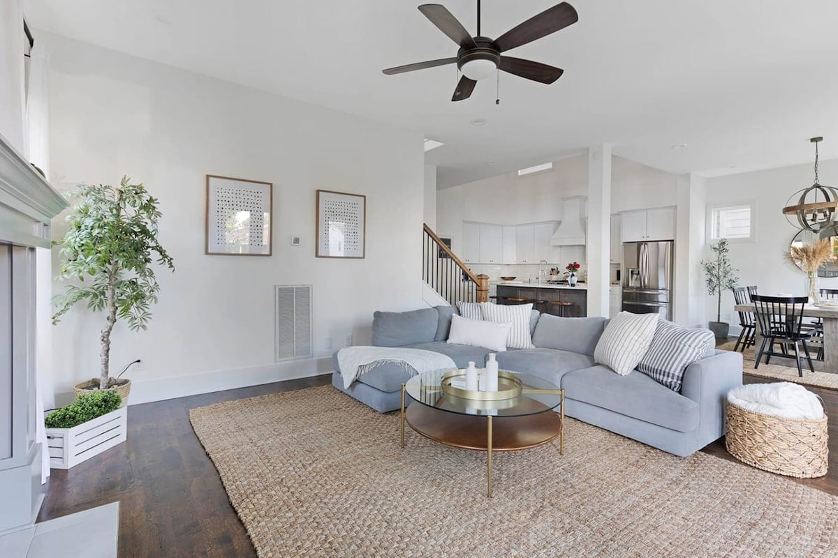 The light and bright living room features a large sectional, open to the kitchen and dining room, creating a spacious and inviting area for entertaining.