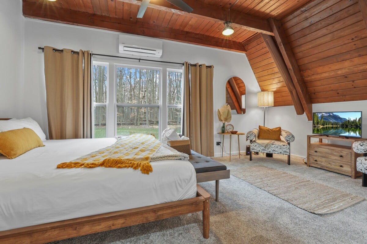 The primary bedroom on the first floor comes with a private full bathroom attached, a massive walk in closet, 2 chairs for relaxing, a view, and a tv.