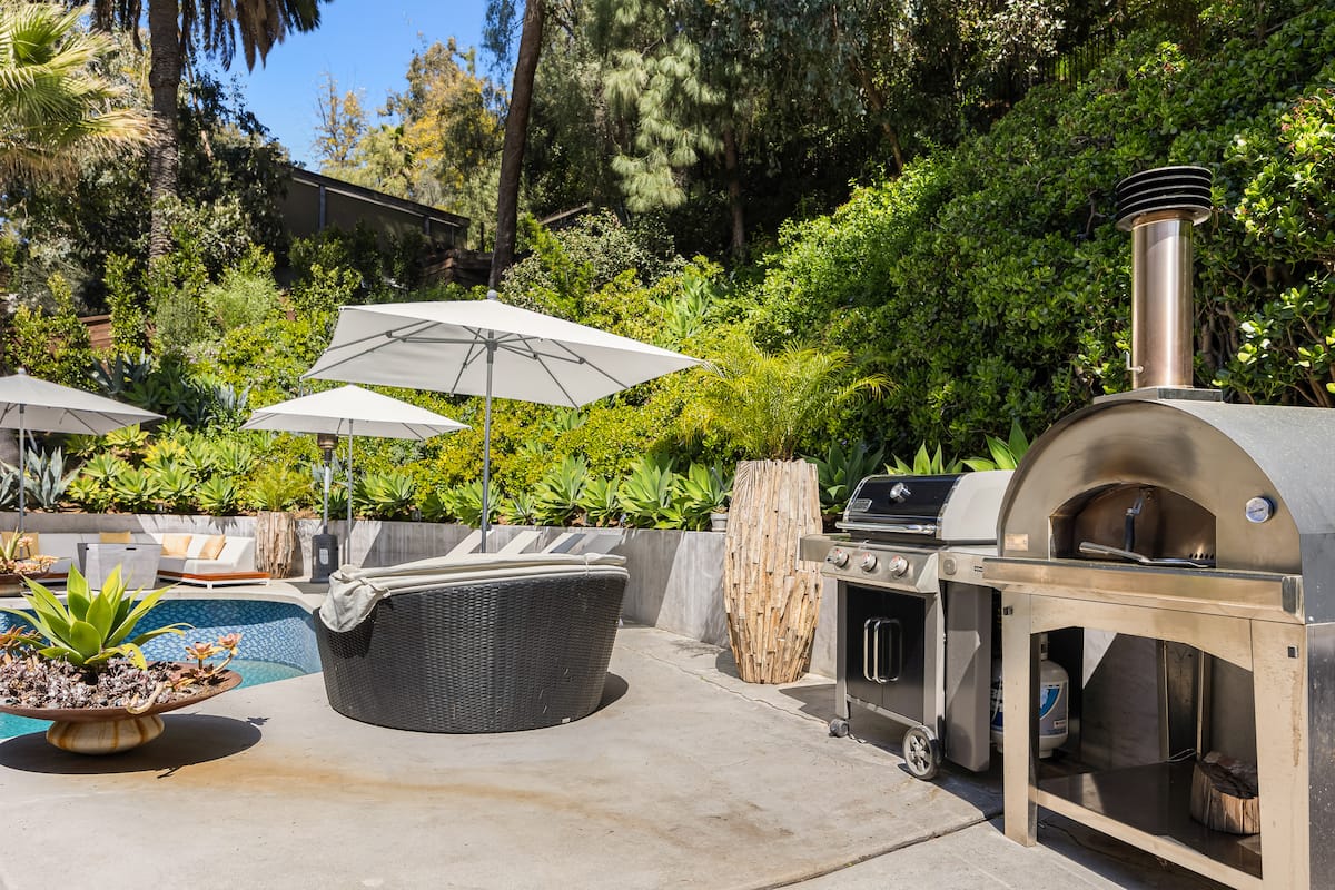 Wood-fired pizza oven and BBQ grill, perfect for outdoor feasts in the sun-kissed pool area.