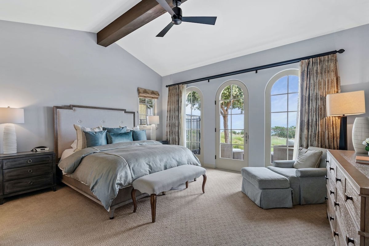 Primary bedroom with sweeping views of the golf course and horizon of the Pacific ocean
