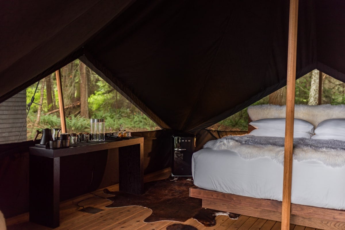 Inside our signature black-out canvas tent: blackout walls, layered linens, and immersive forest views that change with the light.