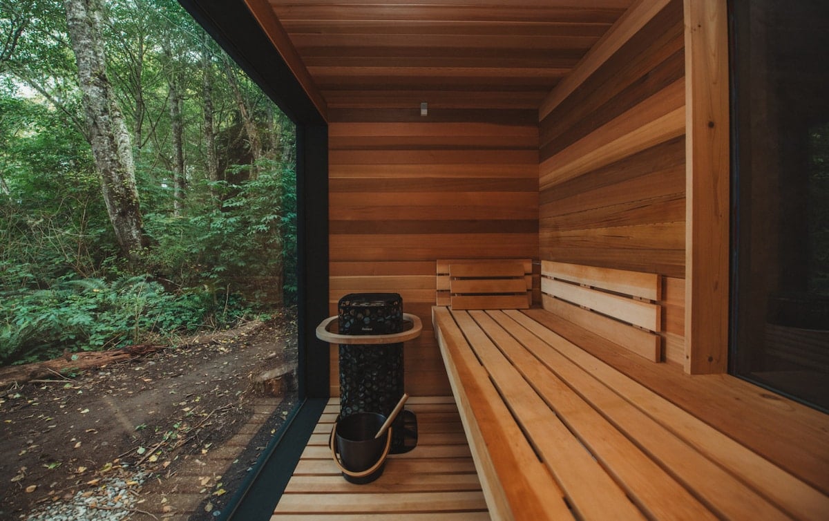 The sauna interior blends Scandinavian simplicity with cedar warmth—offering sea views and deep restoration.