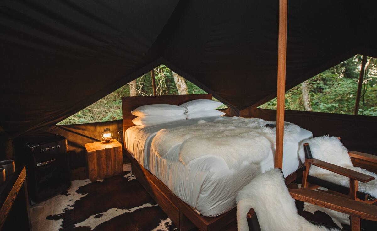 Evening light spills across the king bed in your blackout tent—crafted for rest, stillness, and reconnection.