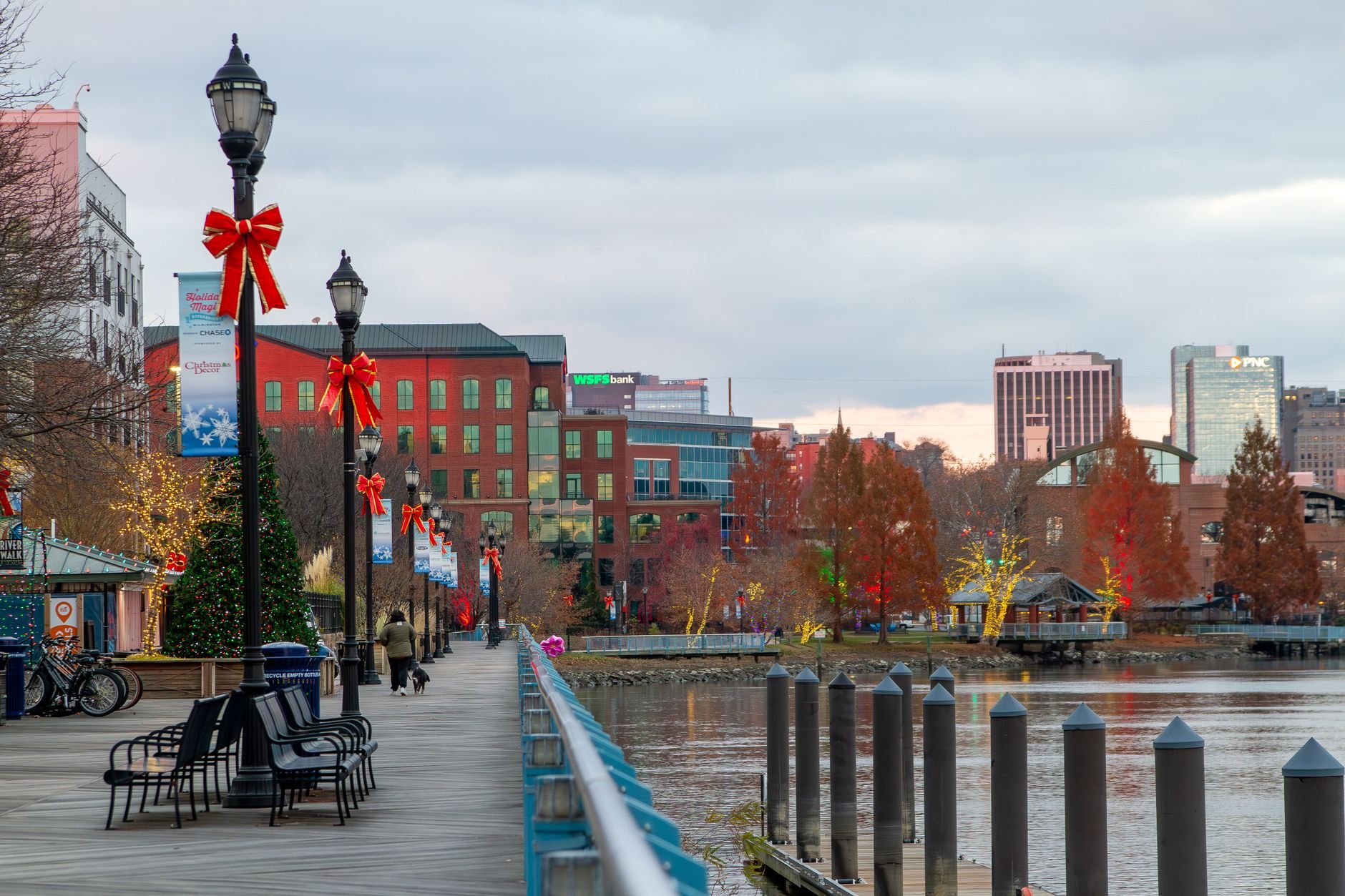 Festively decorated Wilmington riverfront with holiday lights and bows along the walkway.