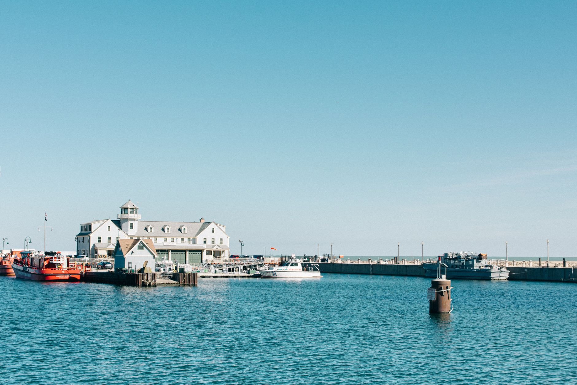 A calm Chicago harbor with boats and buildings under a clear blue sky, perfect for a summer getaway.