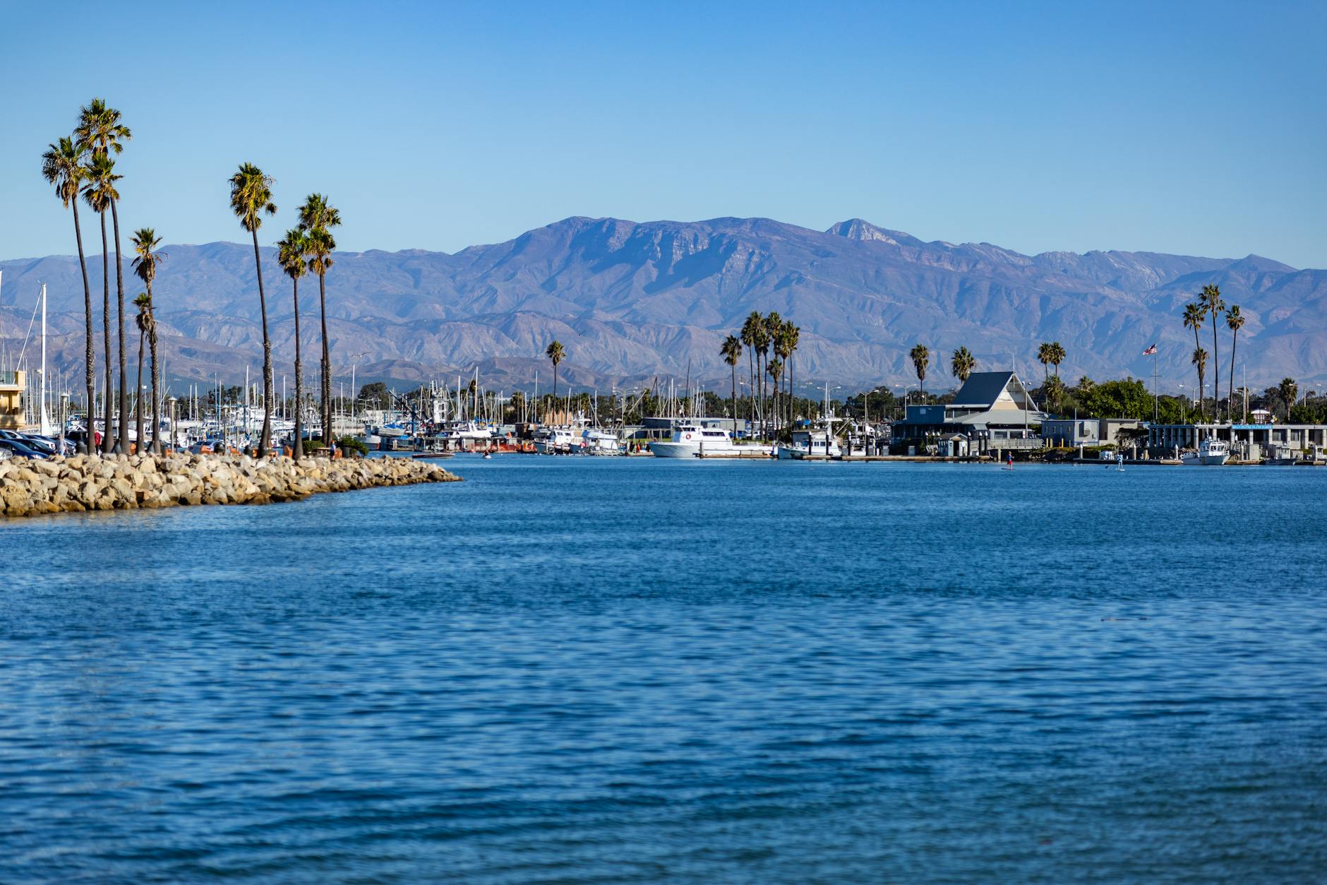 Beautiful view of Channel Islands Harbor in Oxnard, CA with palm trees and mountains in the background.