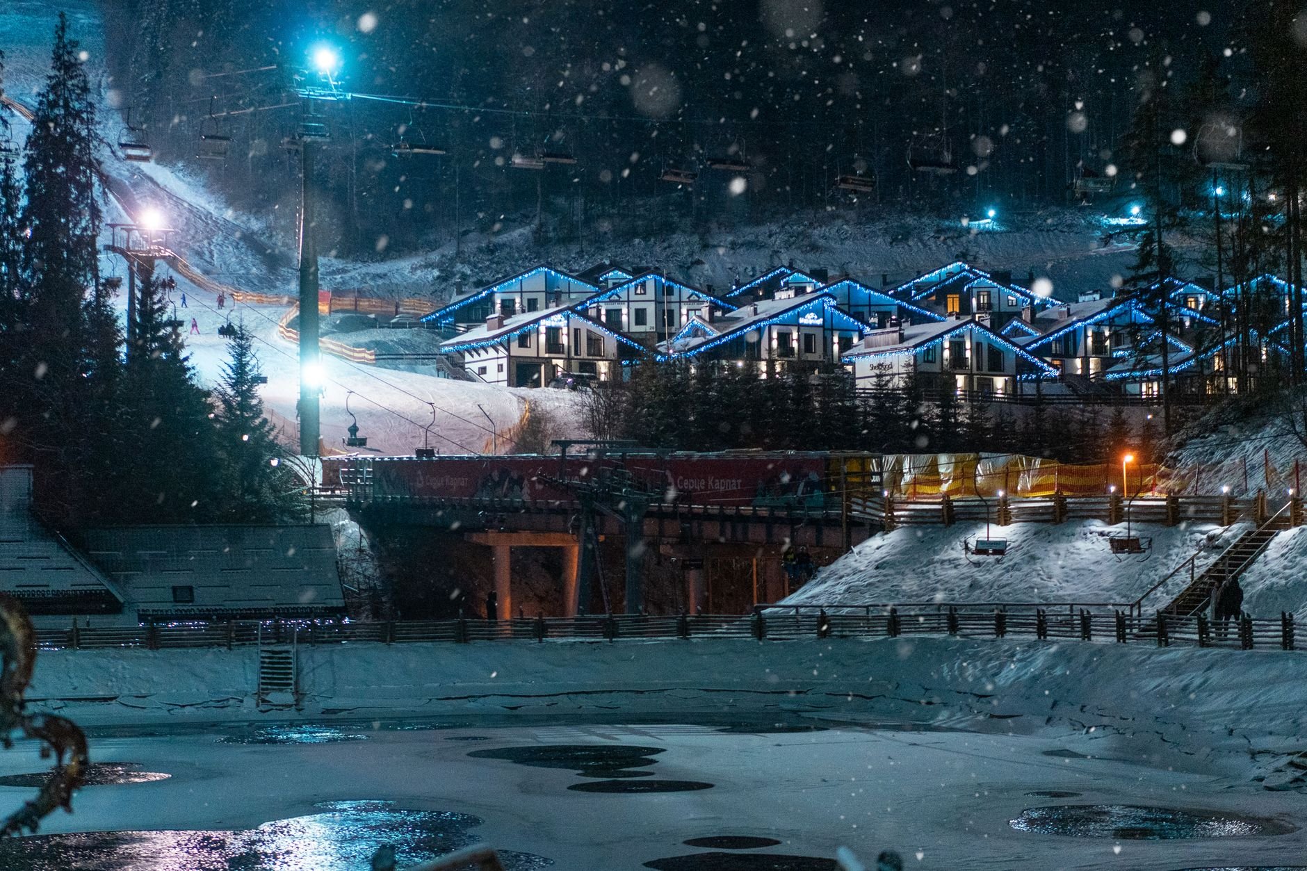 Stunning winter night view of illuminated ski resort in Bukovel, Ukraine with snow.