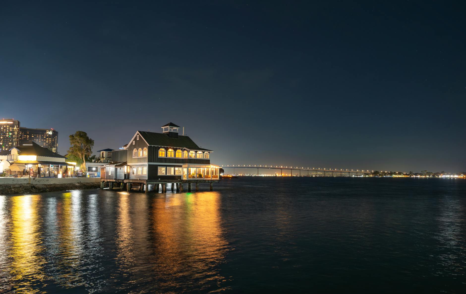 Captivating night scene of San Diego Bay with illuminated waterfront and Coronado Bridge reflection.