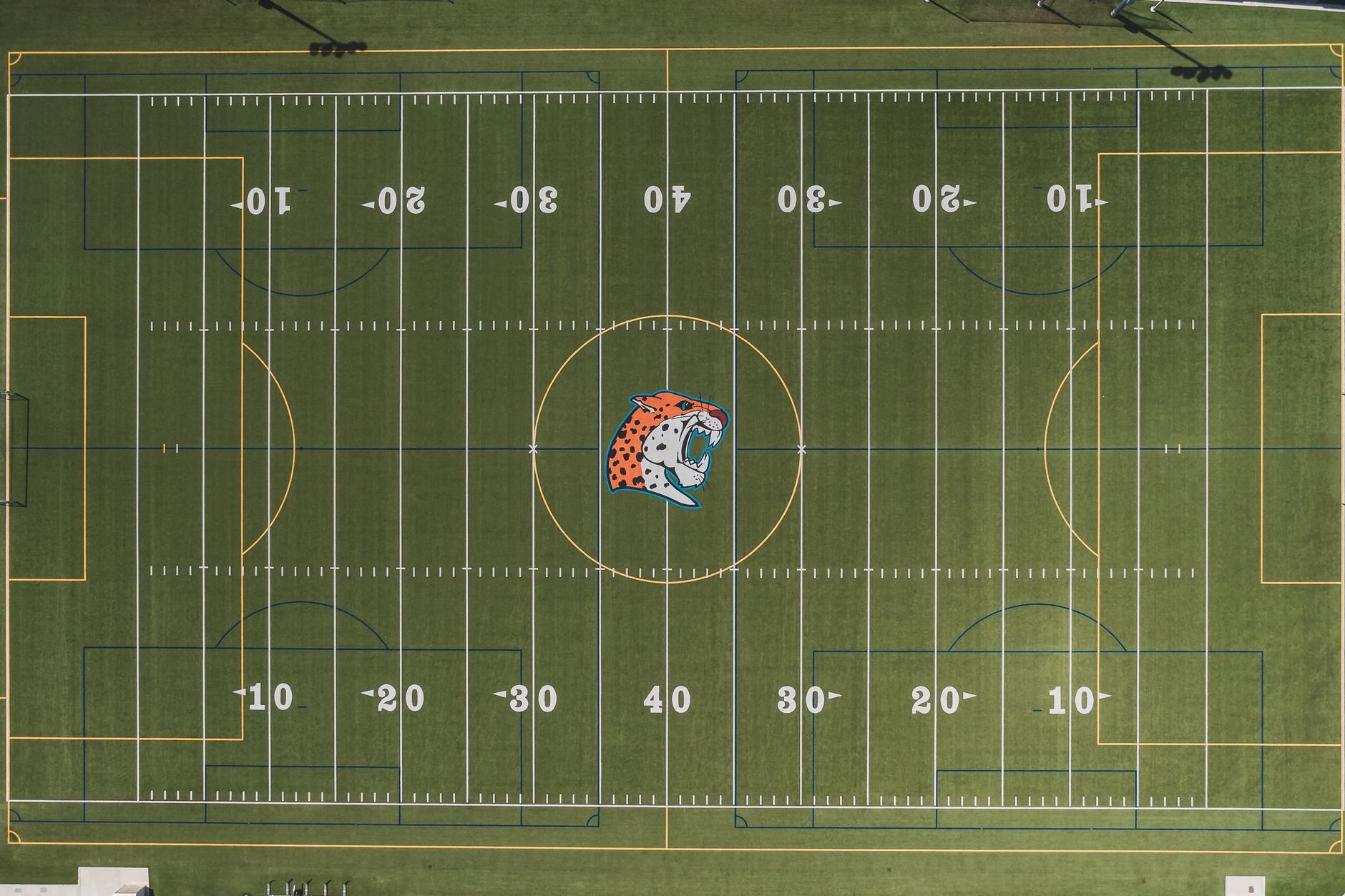 Aerial view of a sports field with visible American football and soccer markings.