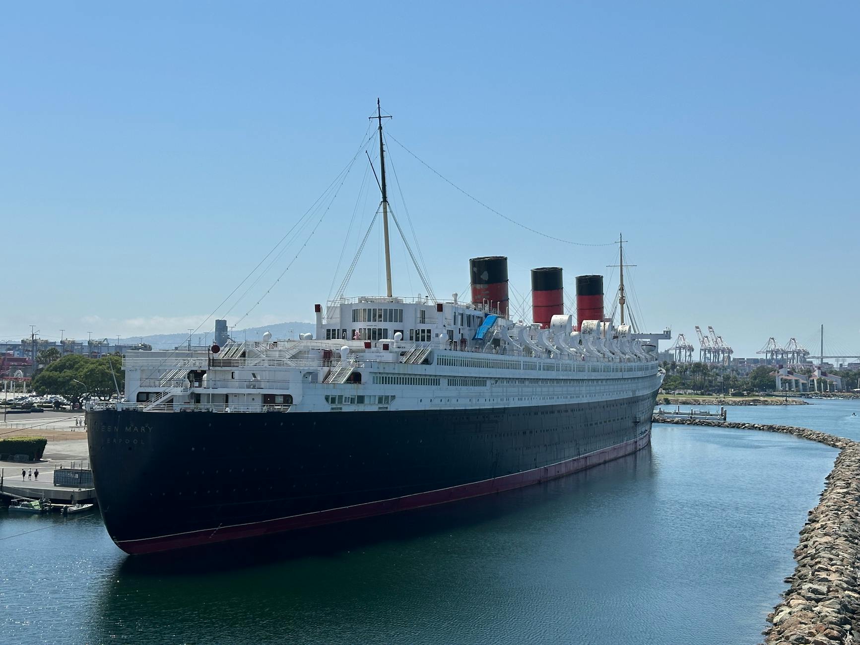Iconic Queen Mary ship docked in Long Beach, California under clear skies.