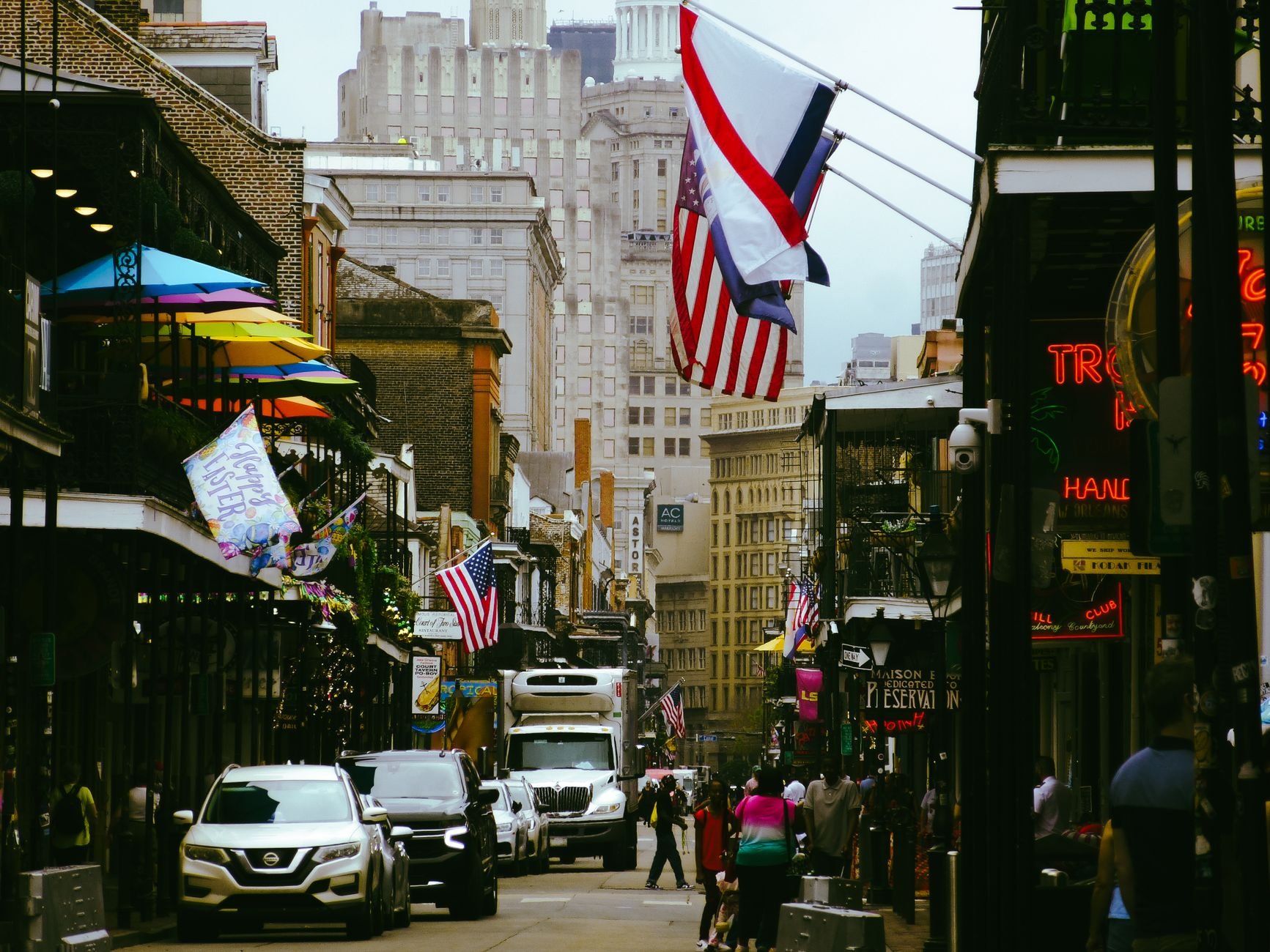 Lively street scene in New Orleans' French Quarter with flags and people.