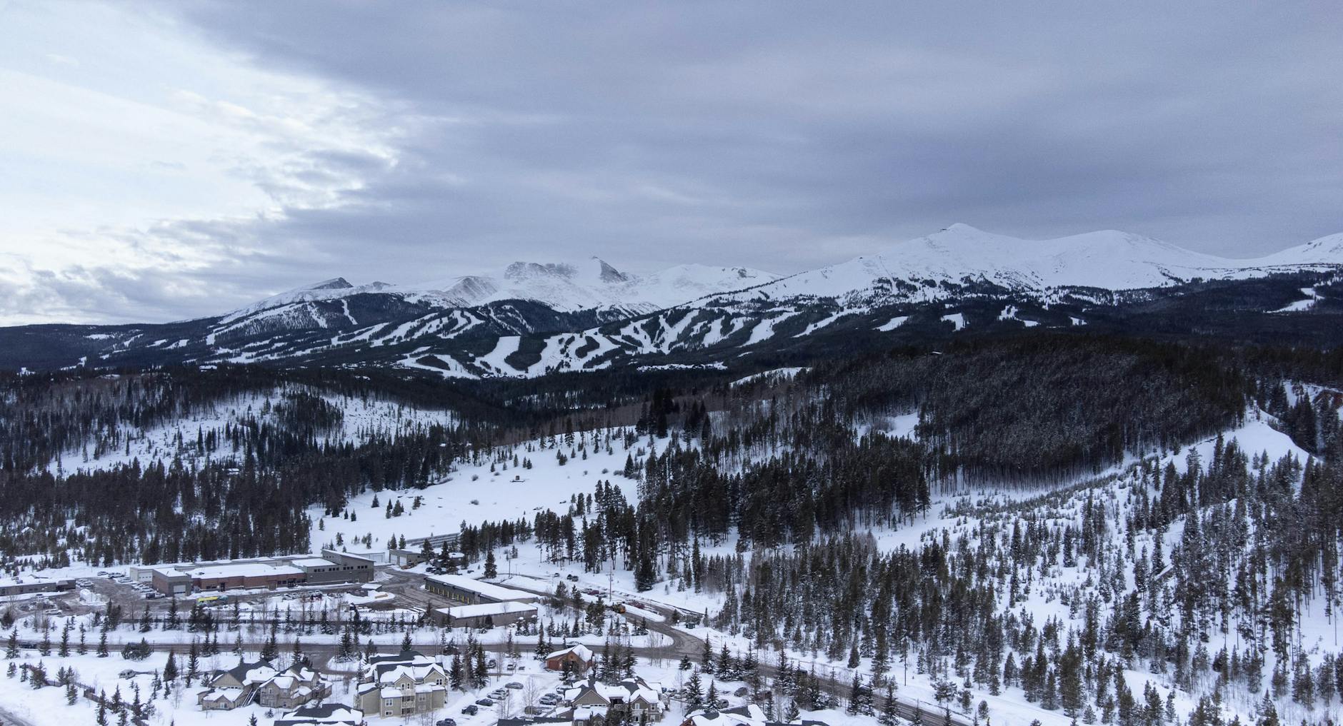 Aerial view of snow-covered mountains and forest in winter.