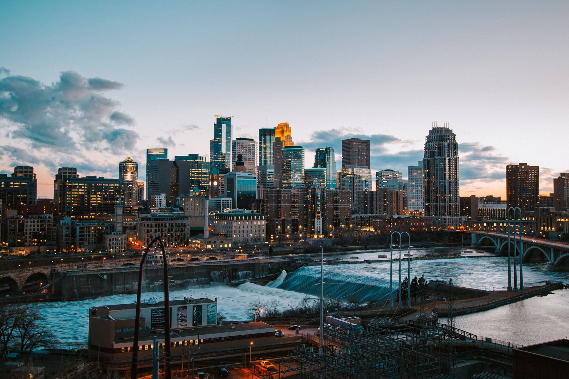 Stunning view of Minneapolis skyline with river and bridge at sunset.